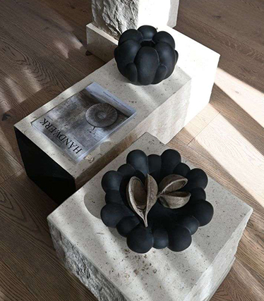 Artistic black ceramic bowls on minimalist stone tables with natural textures