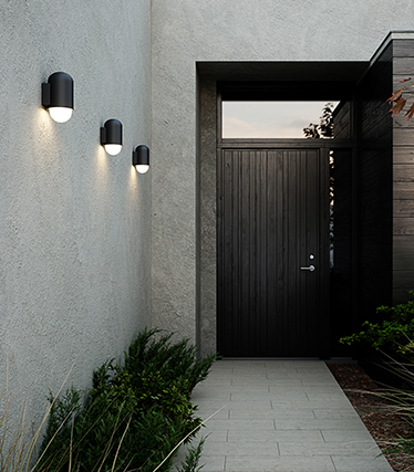 Modern exterior wall lights illuminate the entrance to a contemporary house at dusk.