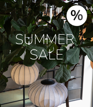 Fabric pendant lights against lush greenery with Summer Sale notice.