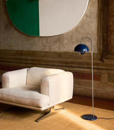 Elegant &Tradition floor lamp beside a modern lounge chair in a warm interior.