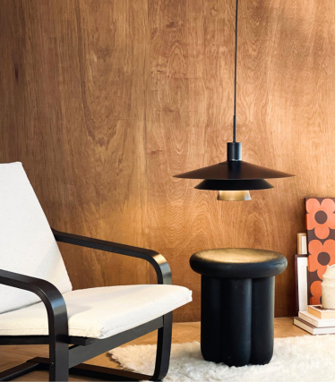 Dyberg Larsen pendant light above a side table and armchair in a cosy interior.