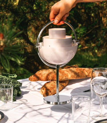 Portable GUBI table lamp on a stylishly set garden table in the sunlight.