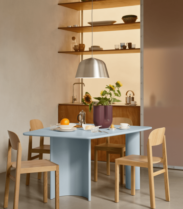Minimalist dining area with pendant light, wooden shelves and table setting.