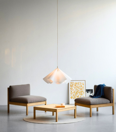 Light pendant light above low armchairs in a quiet, minimalist room.