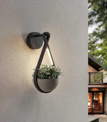 Wall light with integrated planter, warm light on a bright facade.