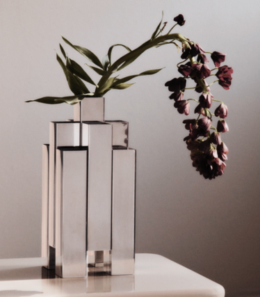 Sculptural vase in polished stainless steel by Ferm Living with dark red flowers