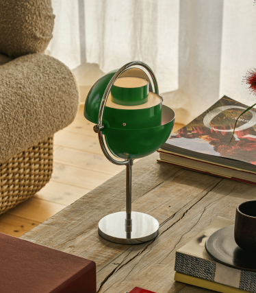 Green Multi-Lite table lamp with chrome base on a wooden table next to books.